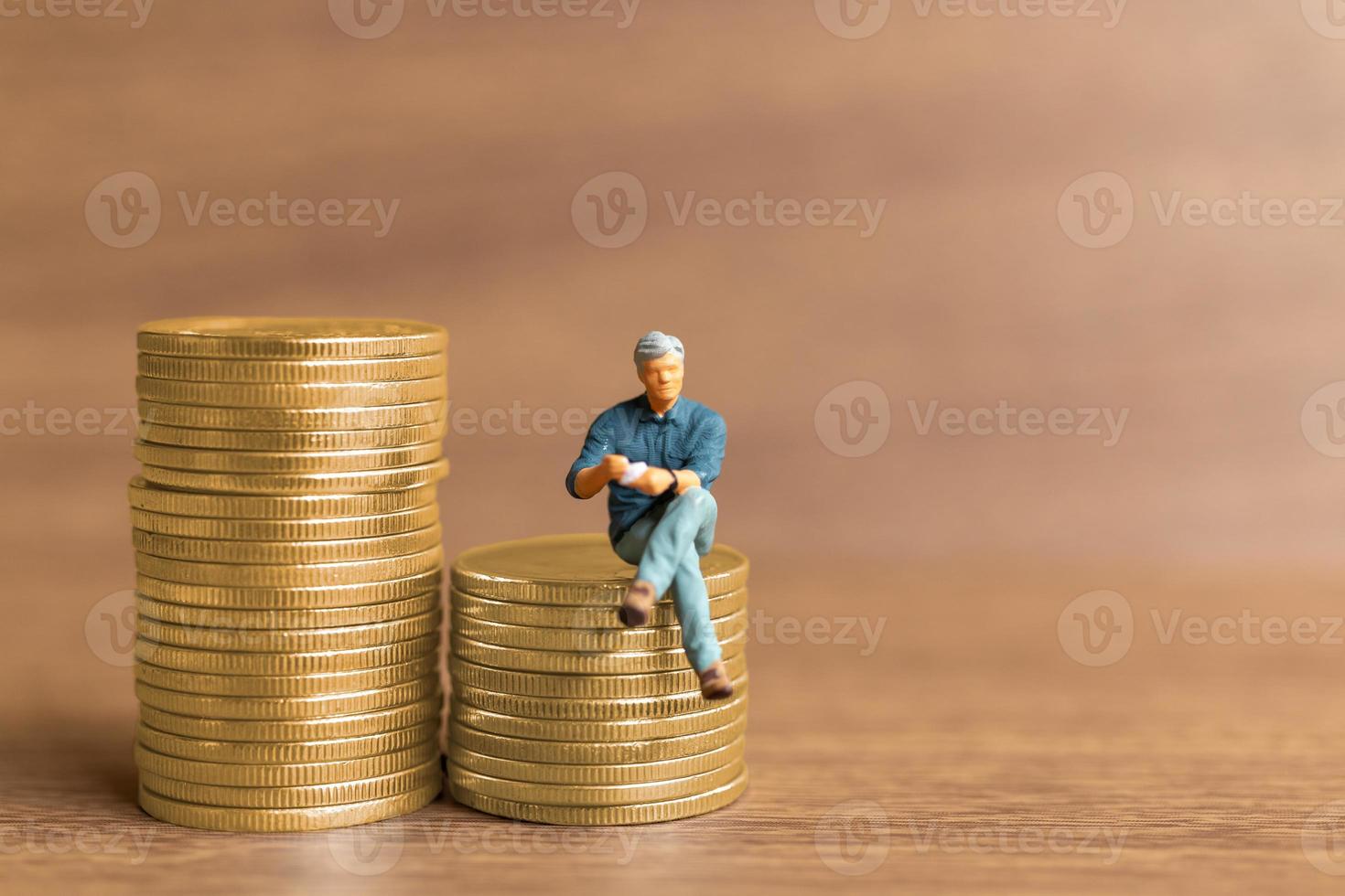 Miniature people A businessman is seated atop a mound of money photo