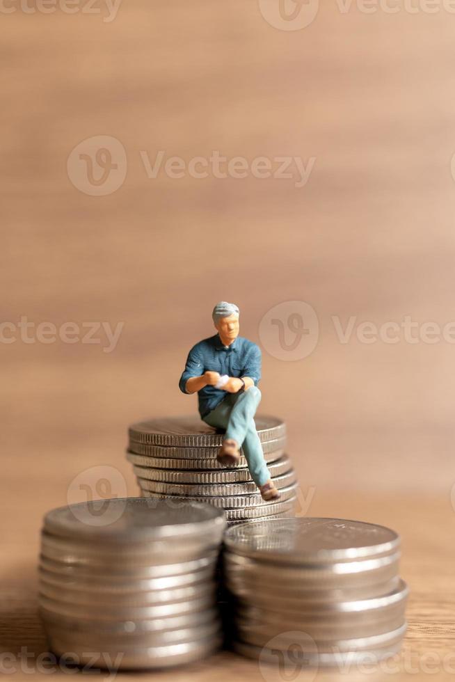 Miniature people A businessman is seated atop a mound of money photo