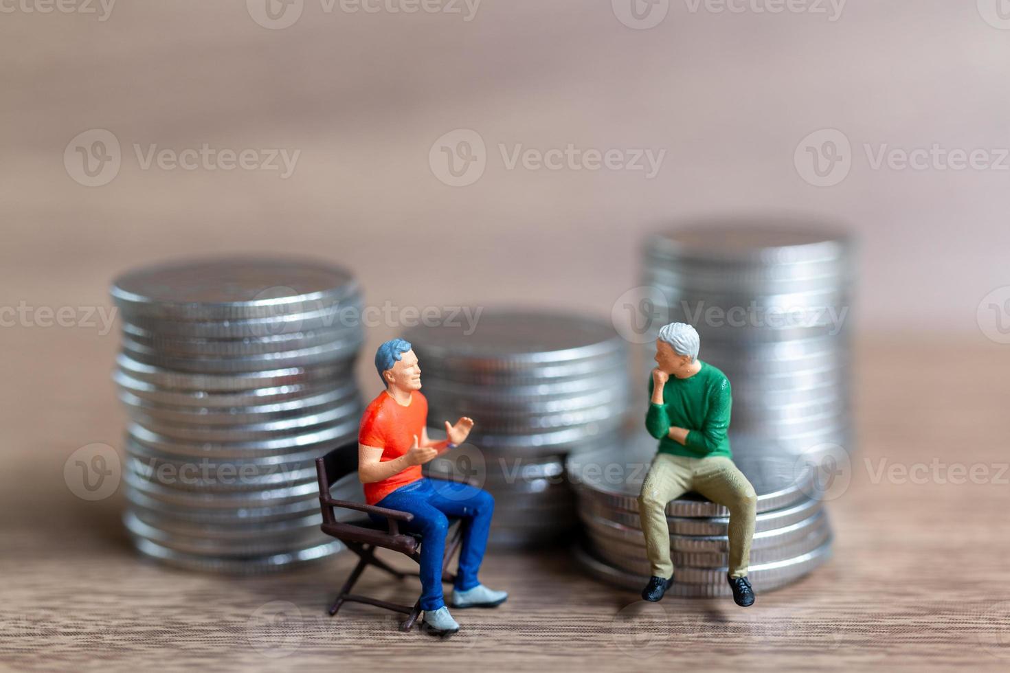 Miniature people A businessman is seated atop a mound of money photo