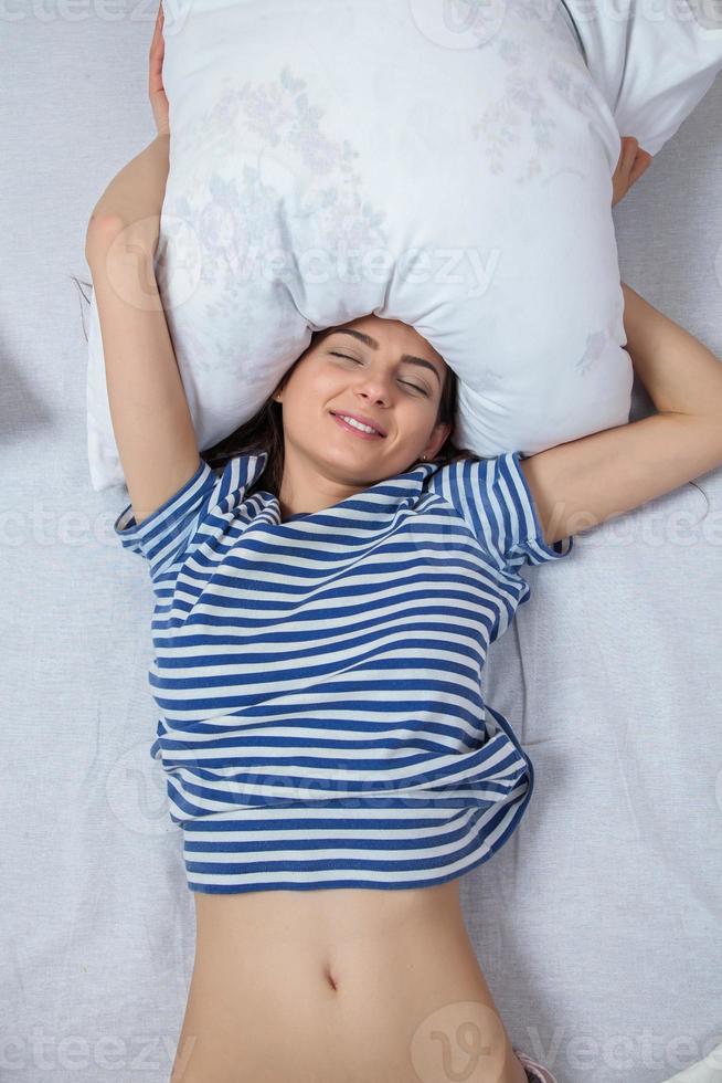 chica duerme en una cama blanca en casa. mujer joven durmiendo en ropa de dormir en el lino blanco en la cama en casa, vista superior. foto