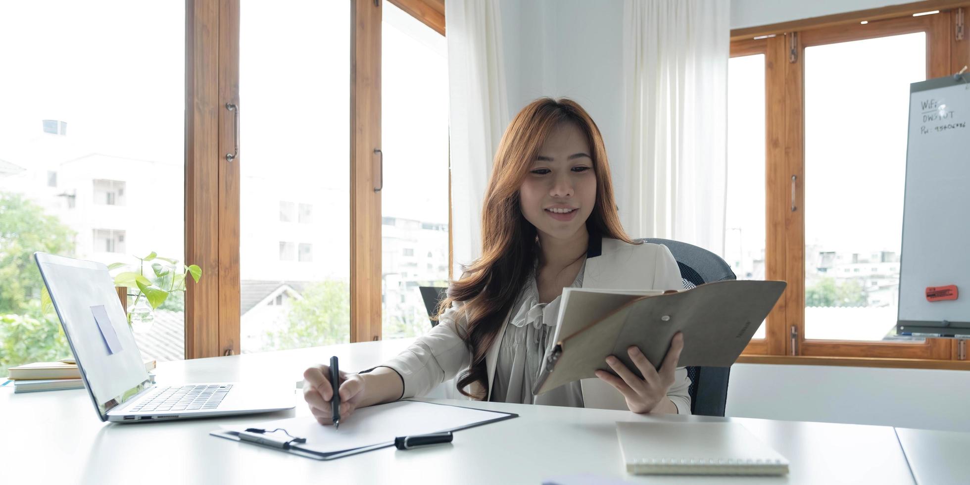 Portrait of an Asian young business Female working on a laptop computer in her workstation.Business people employee freelance online report marketing e-commerce telemarketing concept. photo