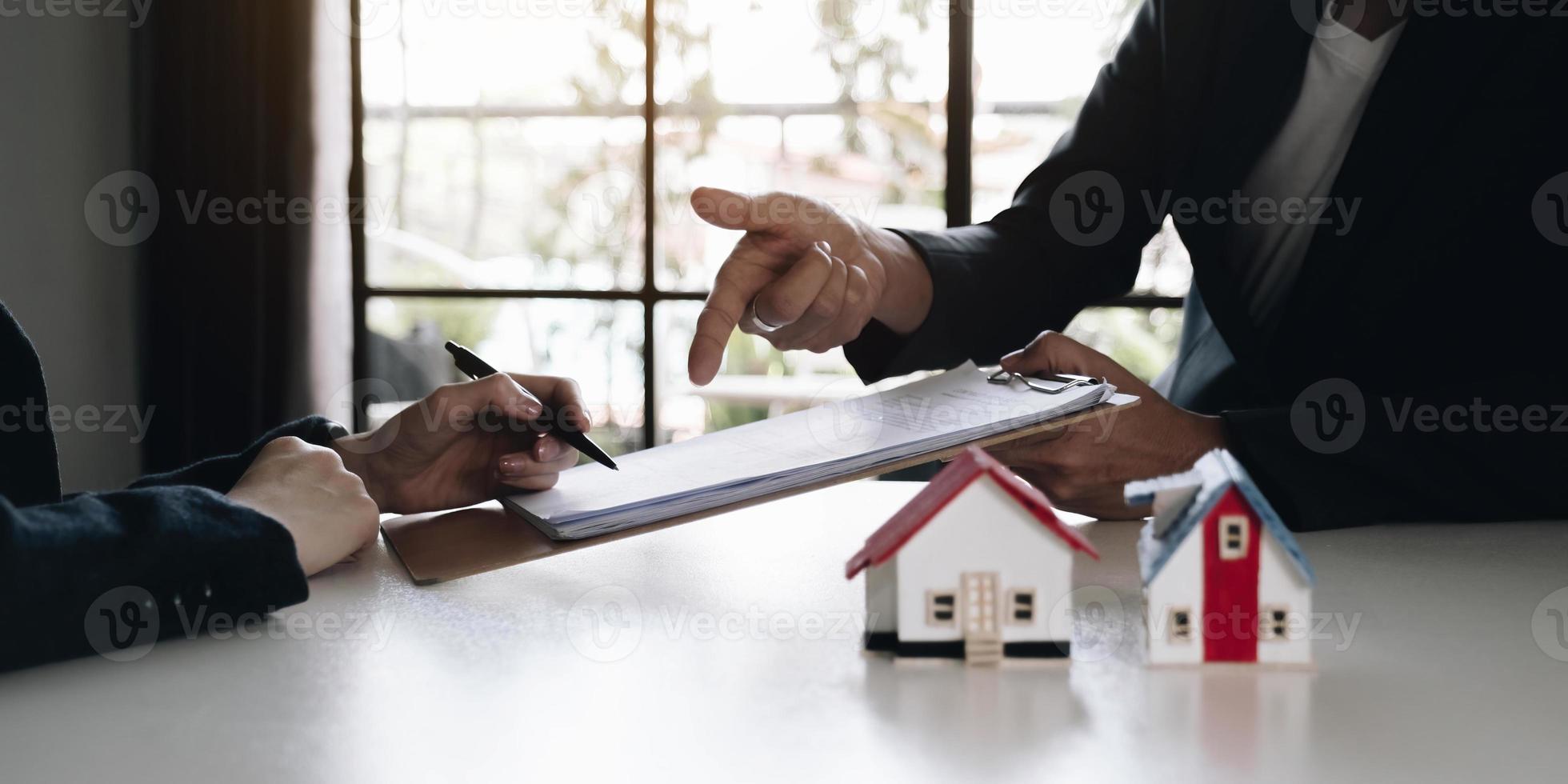 A real estate agent with a House model is talking to clients about buying home insurance. Home insurance concept. photo