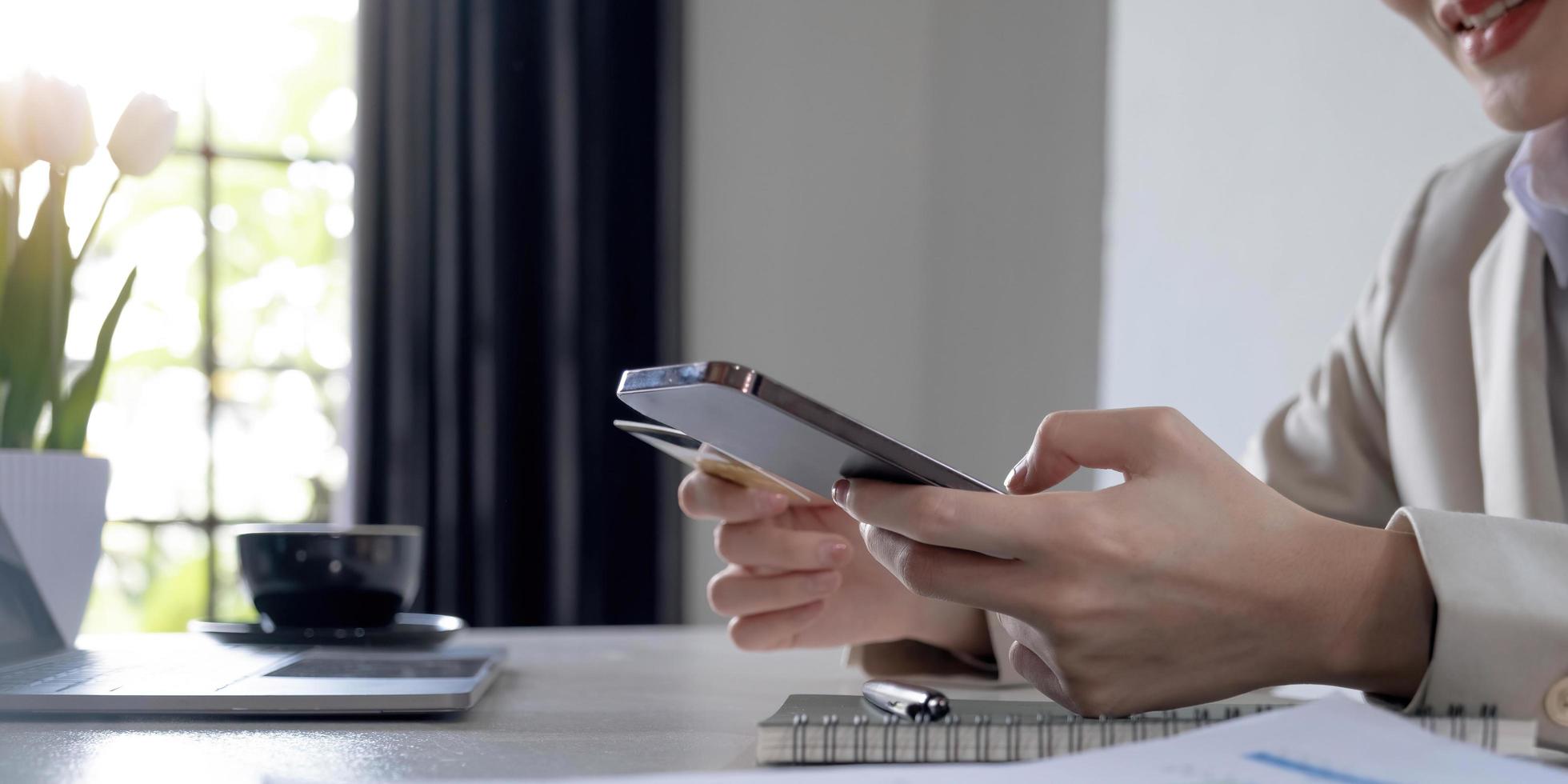 Close up hand of business woman using a credit card and mobile smartphone for payments and online shopping, Online shopping, digital banking, E-commerce concept. photo