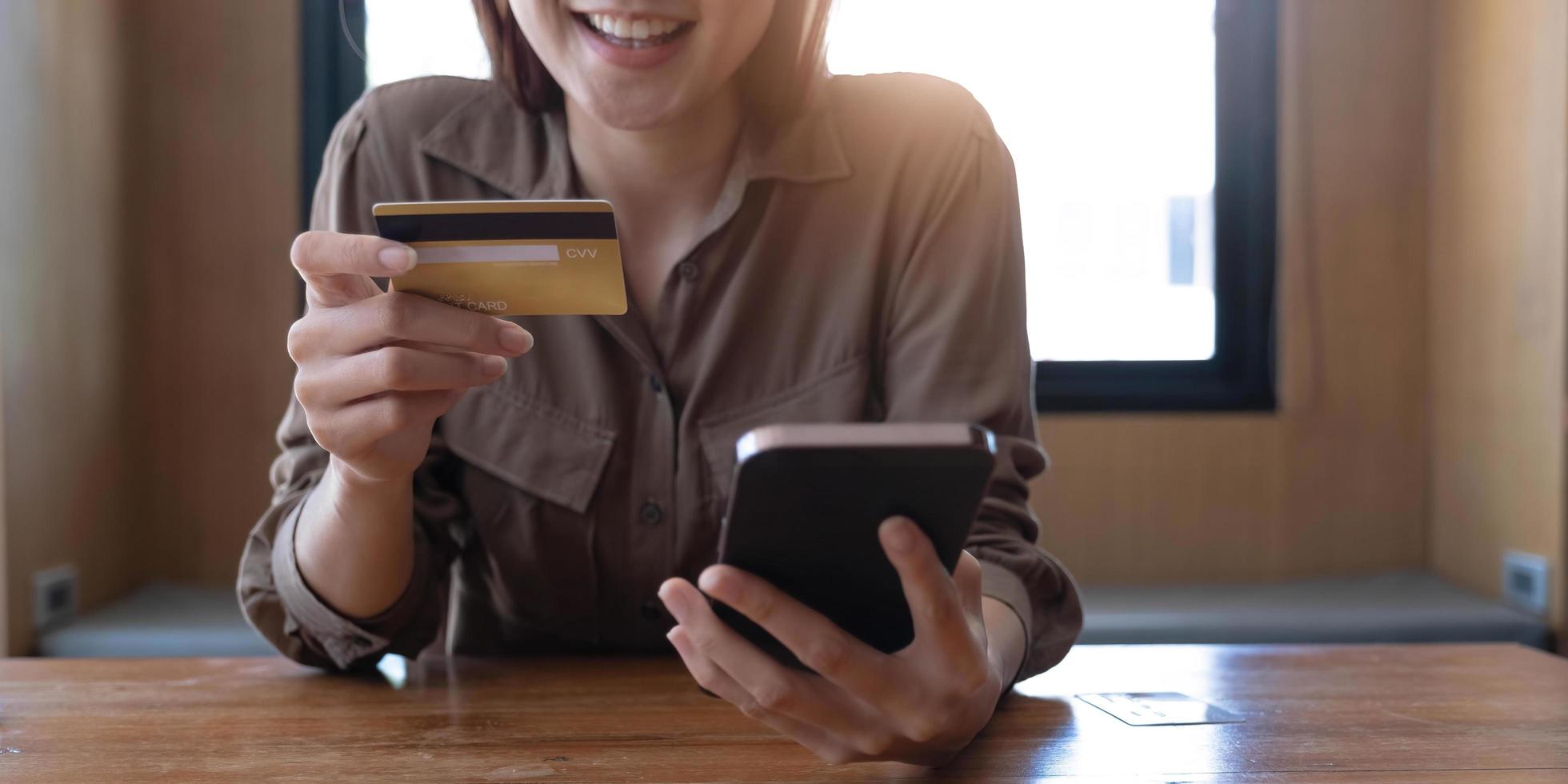 Closeup woman's hands holding a credit card and using smartphone for online shopping. photo