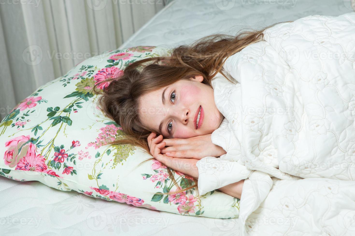 Girl sleeps in a white bed at home. Young woman sleeping in sleepwear on the white linen in bed at home, top view. photo