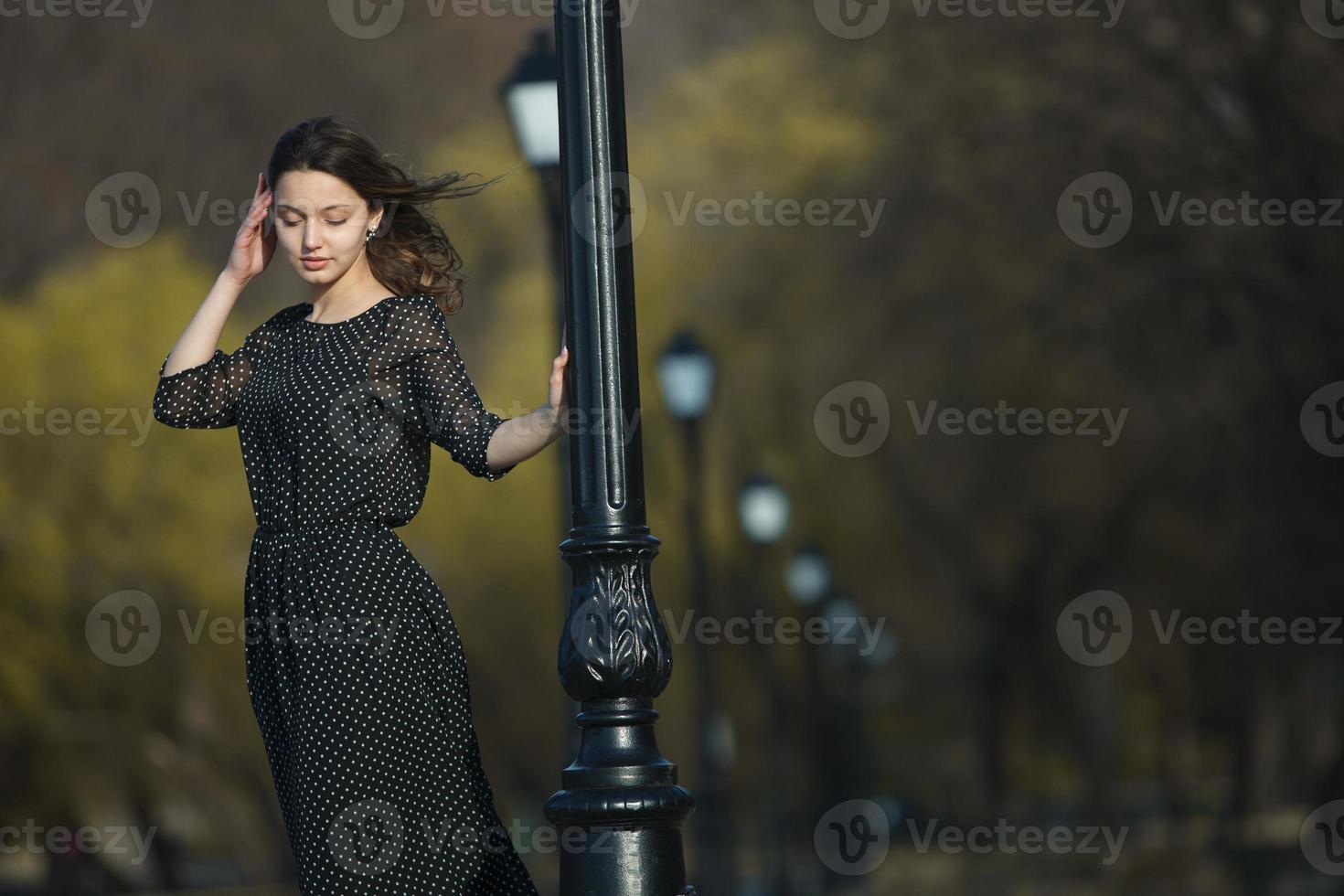 Woman's portrait with a hair moving in the wind. Close-up portrait of young beautiful Russian brunette girl at summer green park. European white woman in dress. photo