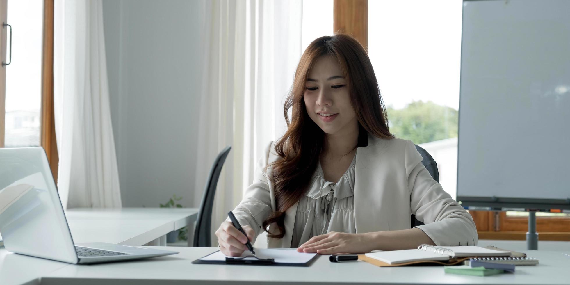 Portrait of an Asian young business Female working on a laptop computer in her workstation.Business people employee freelance online report marketing e-commerce telemarketing concept. photo