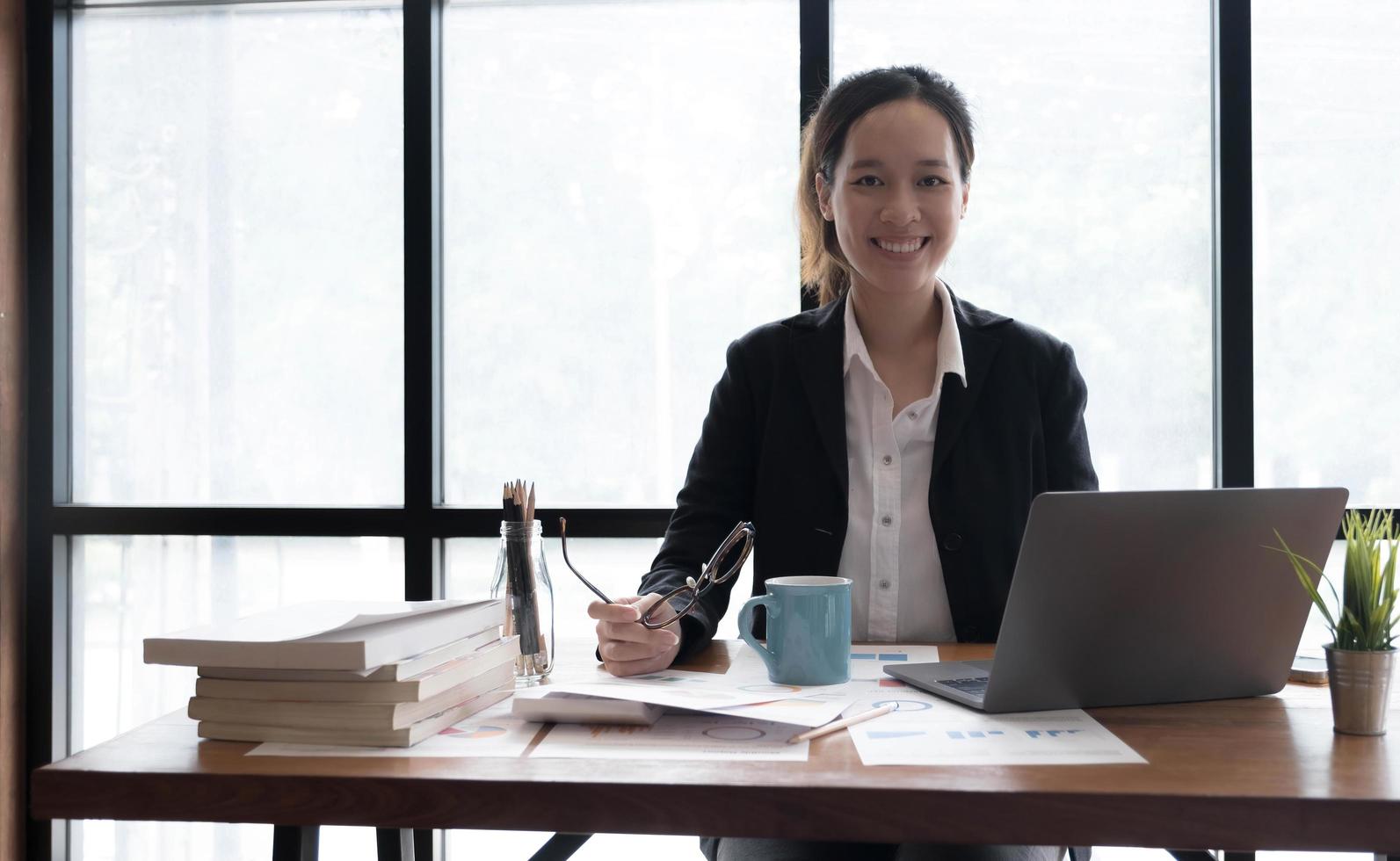 Charming Asian woman working at the office using a laptop Looking at the camera. photo