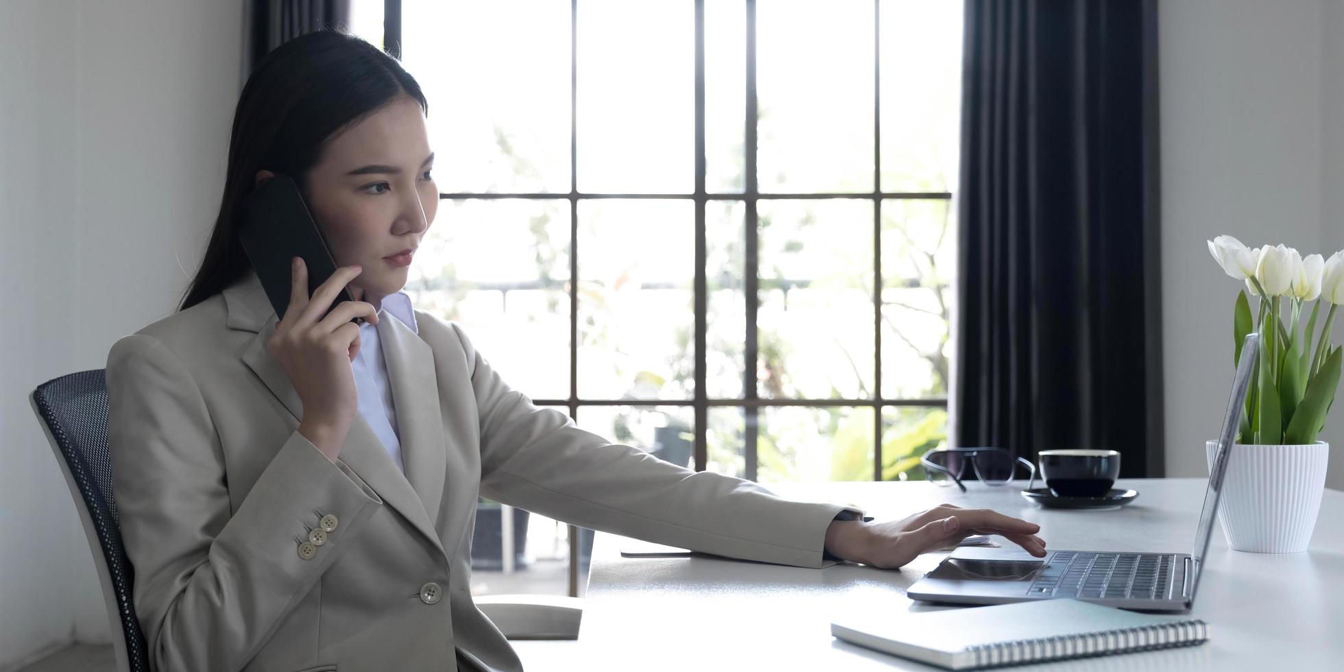 Asian businesswoman talking on a cell phone with a serious expression while working in the office photo