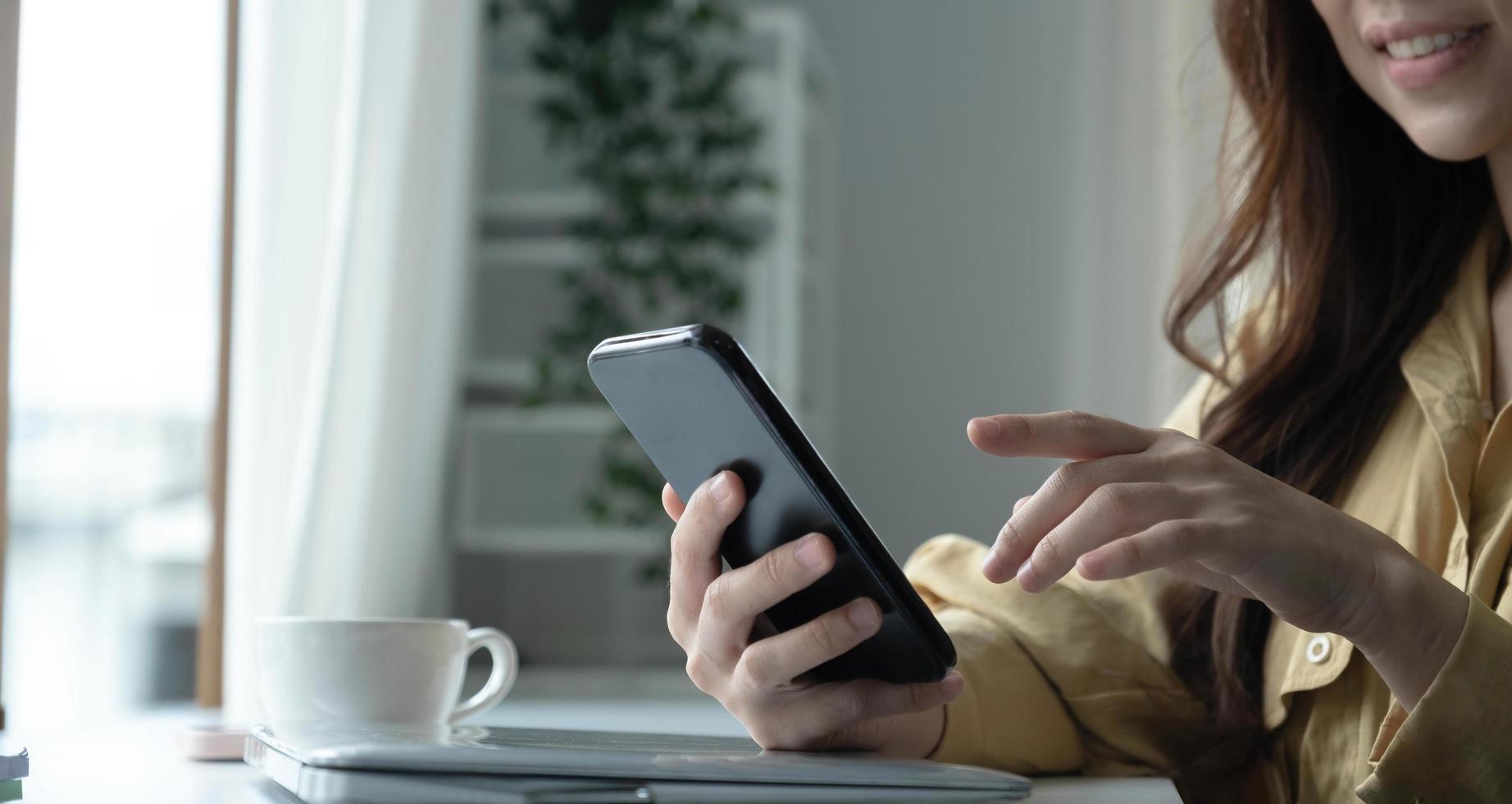 Close up hand of woman using smartphone at coffee shop cafe photo