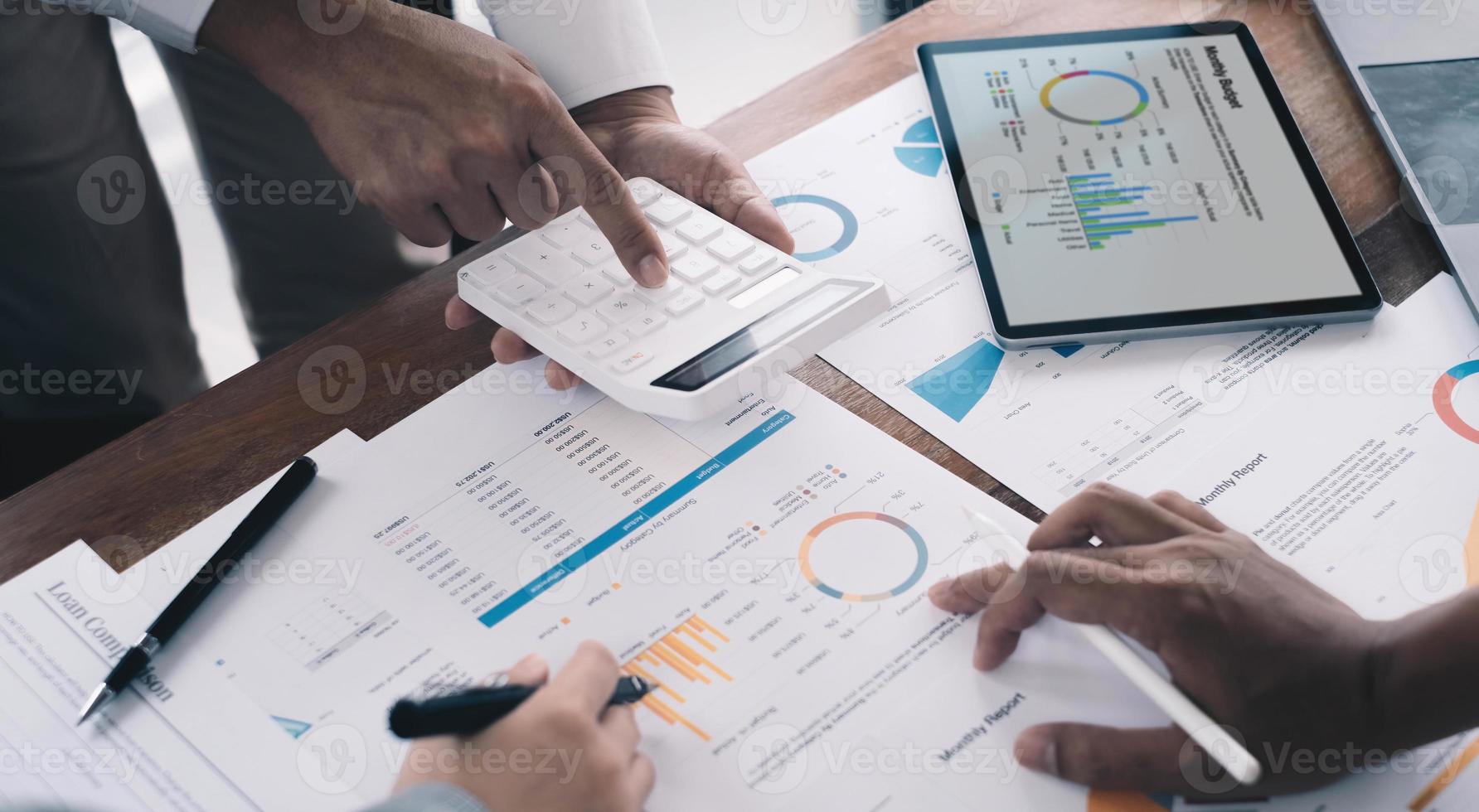 Business man analysis on data paper with business woman using calculator at the office photo