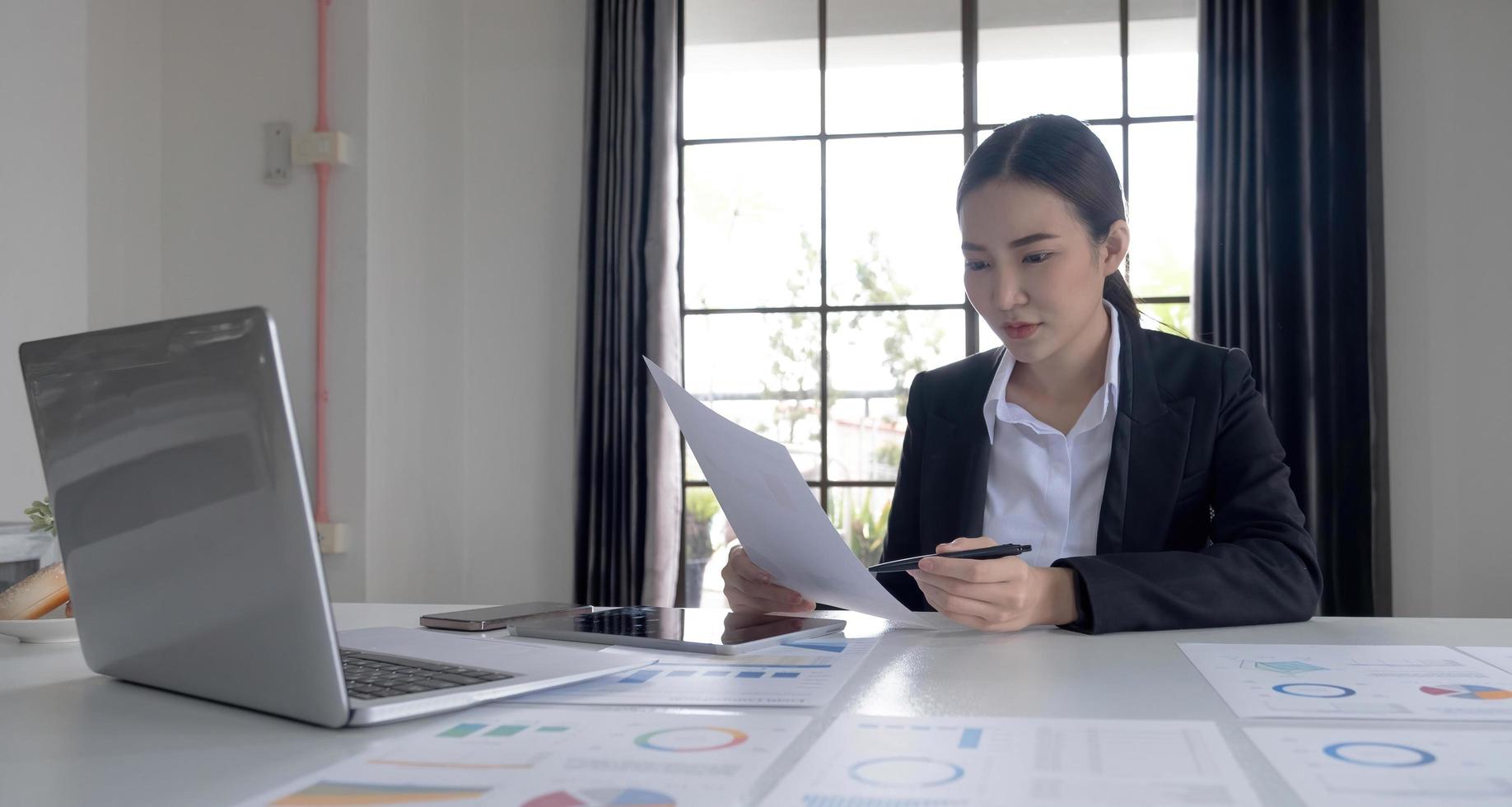 Portrait of an Asian woman working on a tablet computer in a modern office. Make an account analysis report. real estate investment information financial and tax system concepts photo