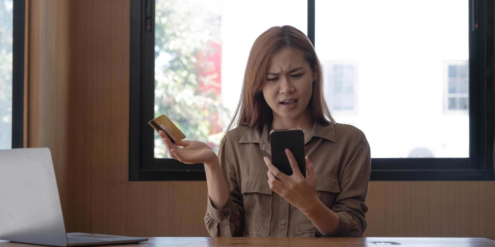 Serious young asian woman complaining her credit card problems with bank's call-centre service. Internet banking problems concept photo