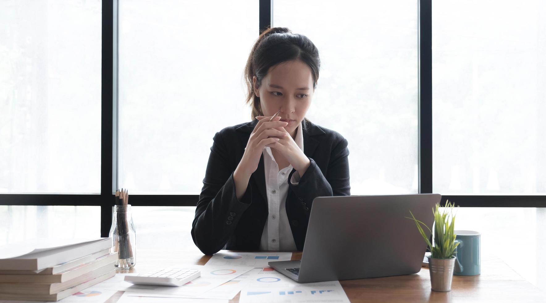 Image of an Asian woman who is tired and overthinking from working with a tablet at the office. photo