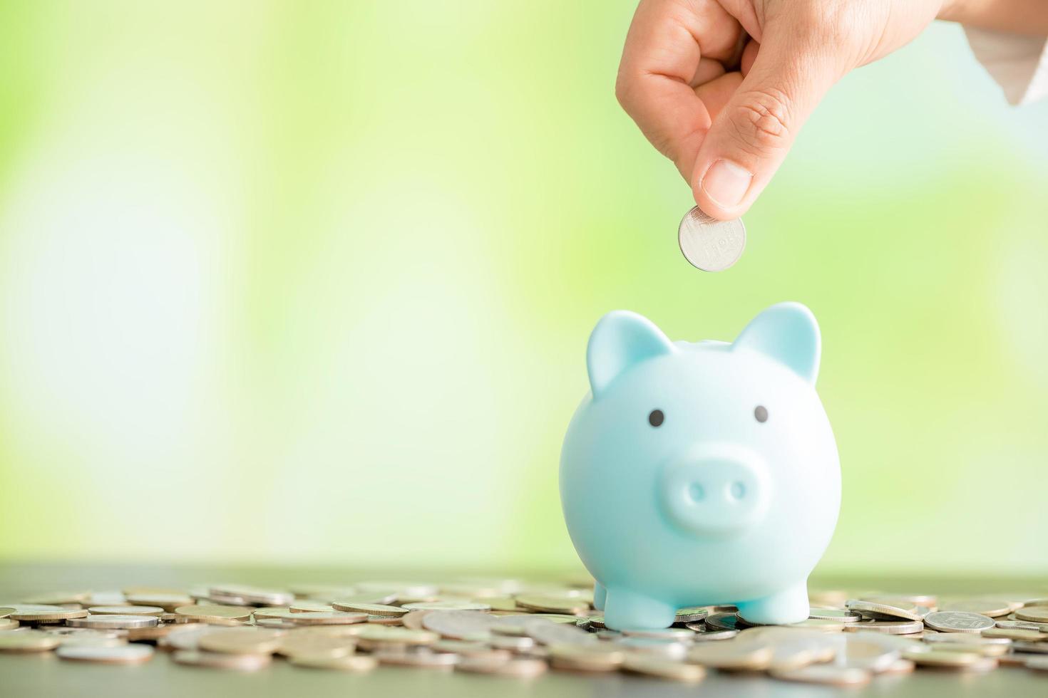 Hand putting coin in a piggy bank photo