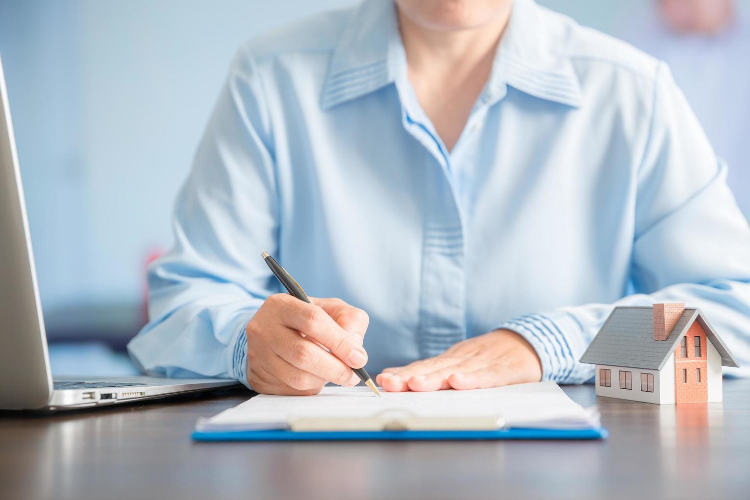 Businesswoman choosing mini house model from model on wood table photo