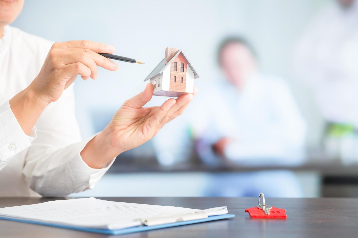 Businesswoman choosing mini house model from model on wood table photo