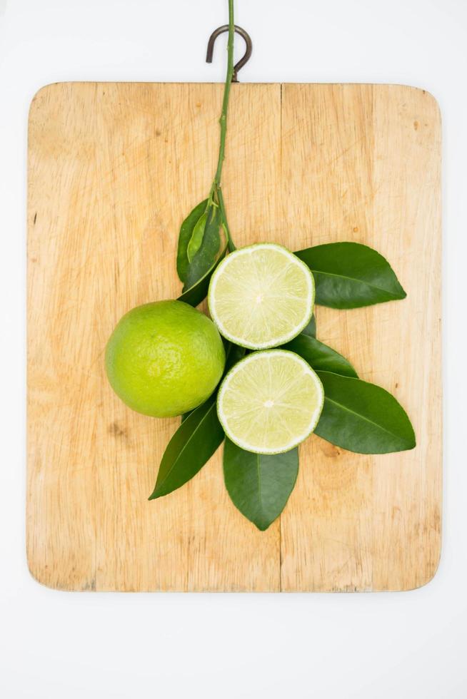 lime and leaves on wooden cutting board on white photo