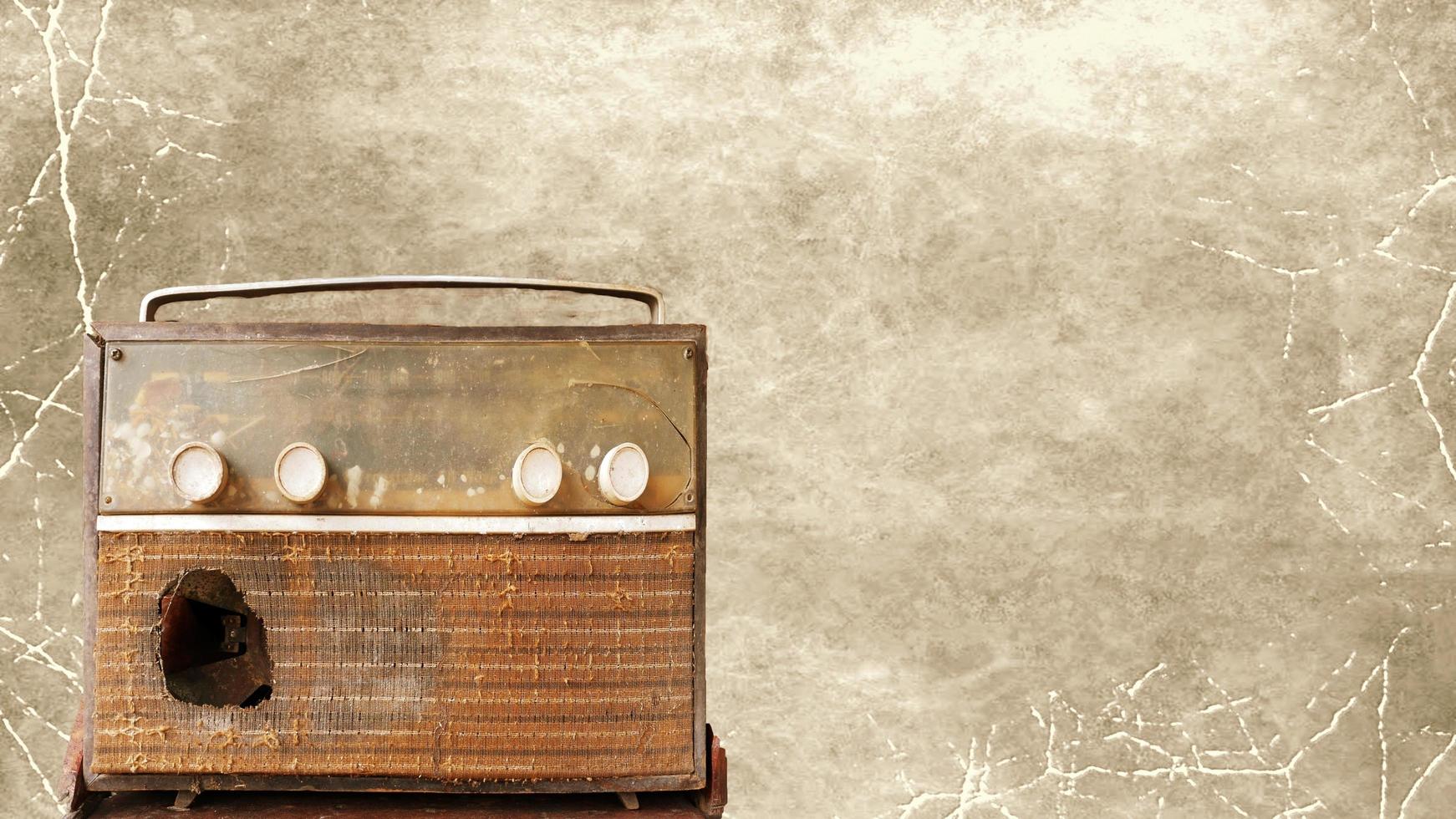 A very old, damaged radio player with an old picture background. photo