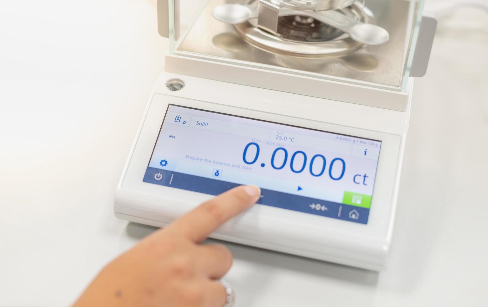 Female hand push the digital Hydrostatic Weighing Balance for examine the specific gravity for separate the type of precious stone. photo