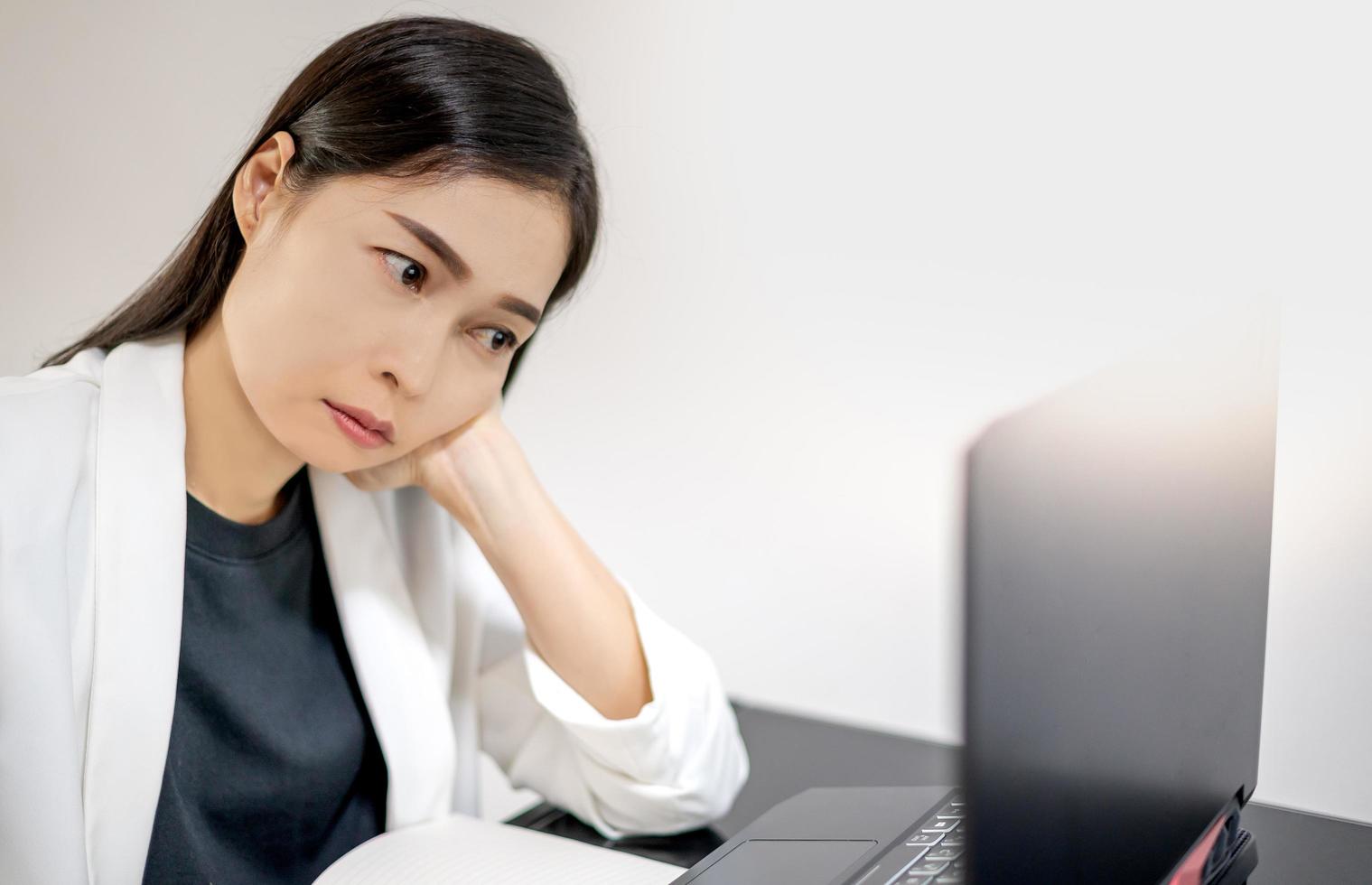 Asian young feeling stress from work, while sitting in front of the laptop in their home. photo
