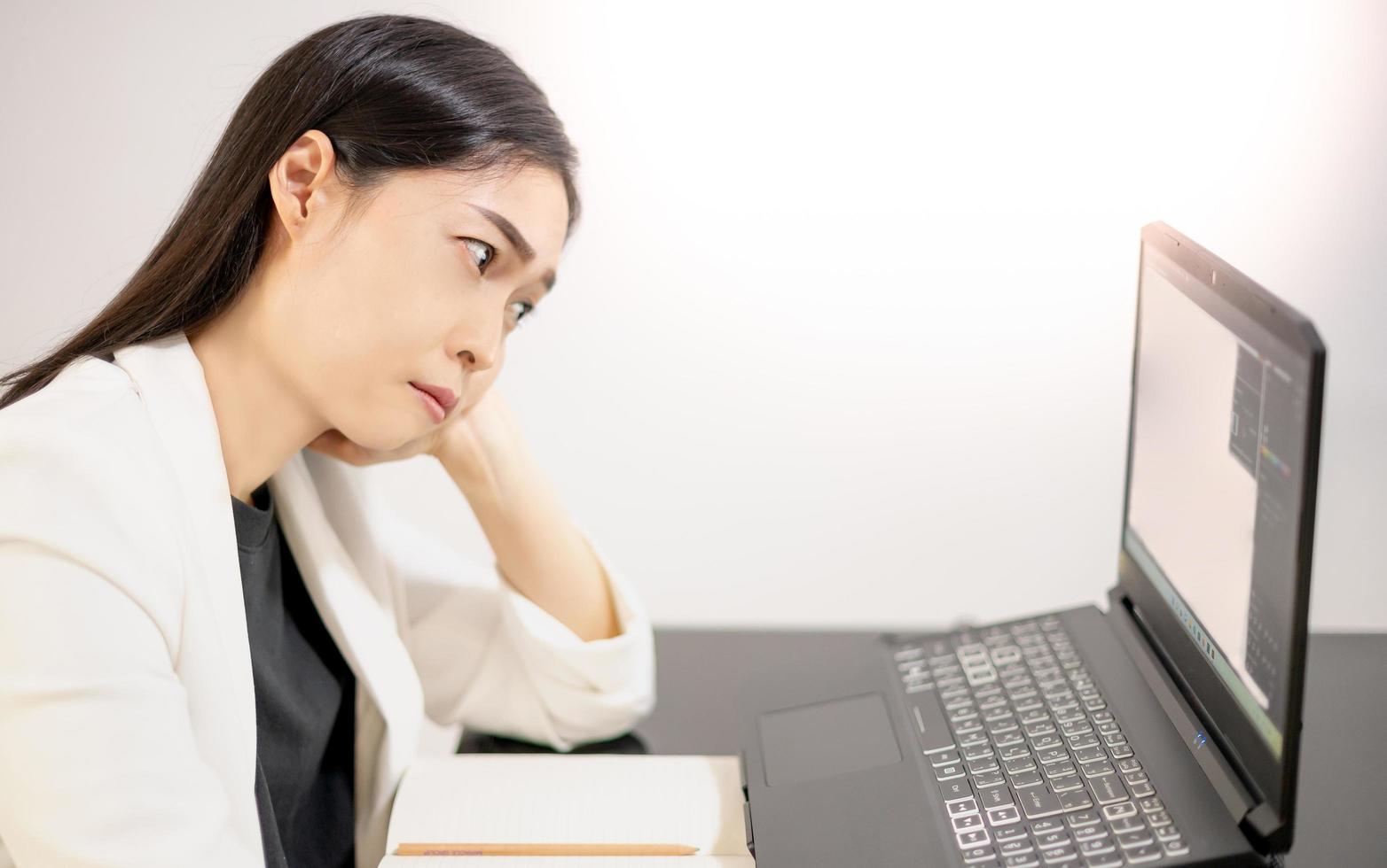 Asian young feeling stress from work, while sitting in front of the laptop in their home. photo