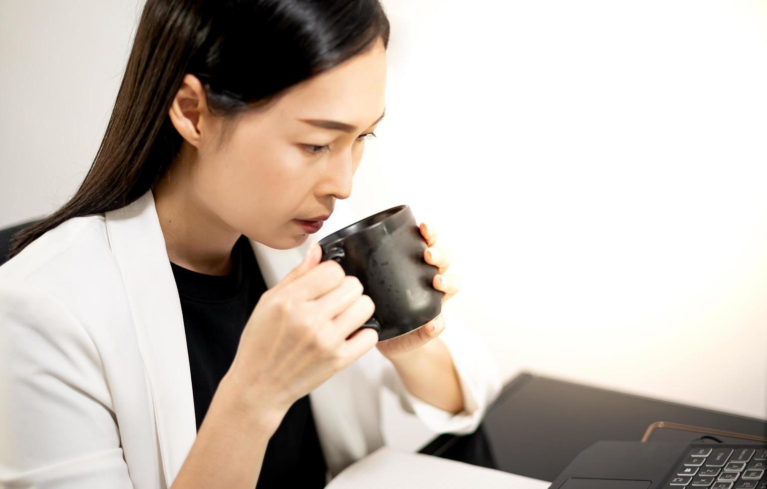 Female hand holding glass while working with the laptop computer. photo