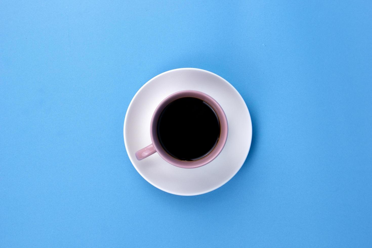 An isolated black coffee on light pink cub on blue background used for adveretising design photo