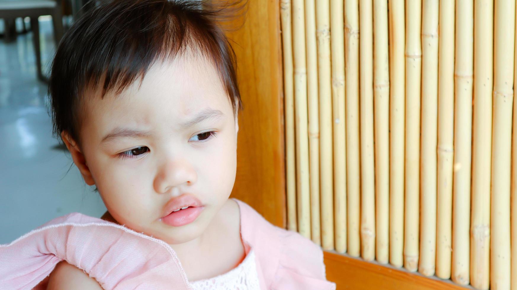 Little toddler child with adorable short hair standing with worried expression at home photo