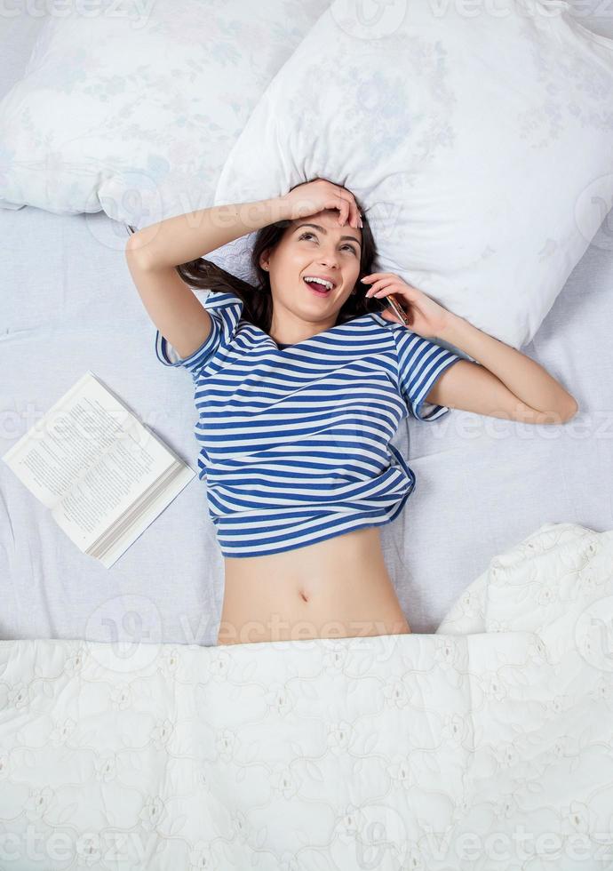 chica duerme en una cama blanca en casa. mujer joven durmiendo en ropa de dormir en el lino blanco en la cama en casa, vista superior. foto