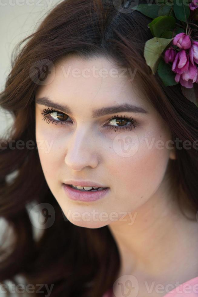 hermosa chica europea blanca con piel limpia en el parque con árboles en flor foto