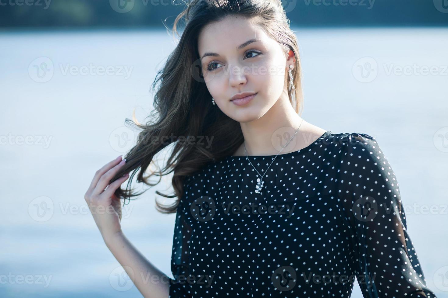 Woman's portrait with a hair moving in the wind. Close-up portrait of young beautiful Russian brunette girl at summer green park. European white woman in dress. photo