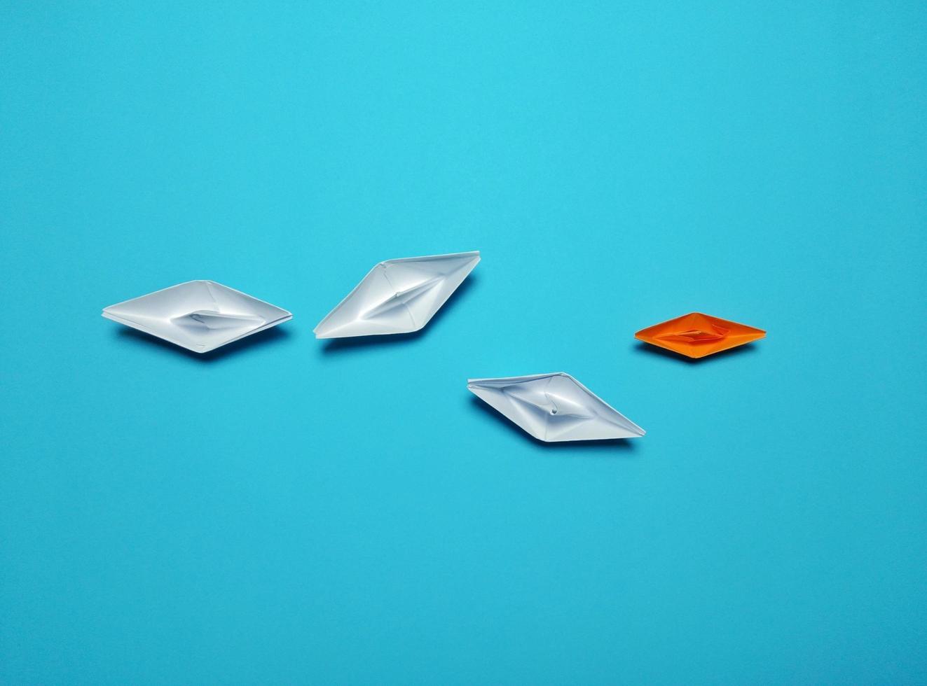 orange and white paper boat on the blue background gives the concept of leadership and a high level of efficient management give a feeling of unity, harmony, love, harmony, success photo