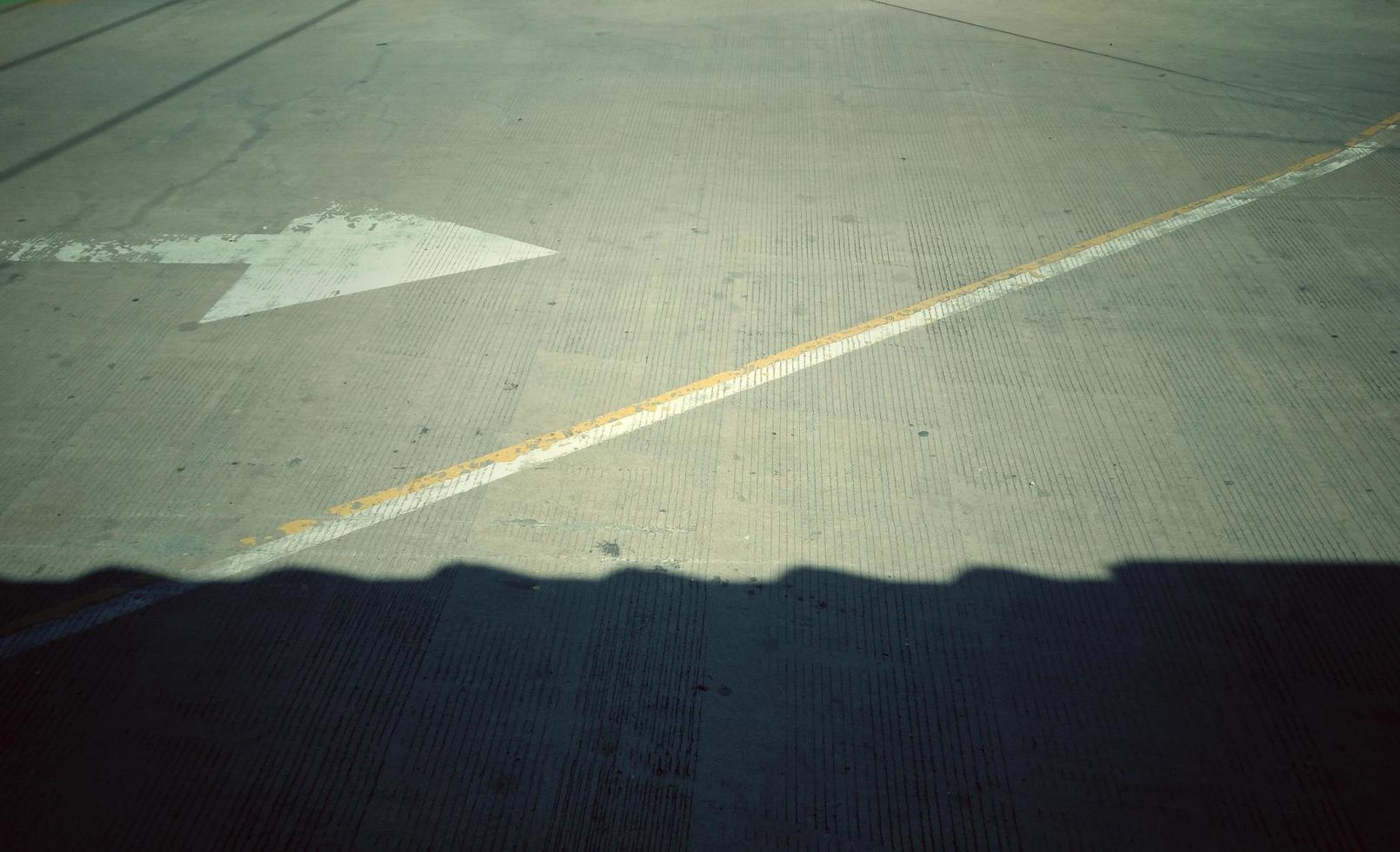 The black shadow on concrete with a white arrow pointing to the right, giving the idea of direction. photo