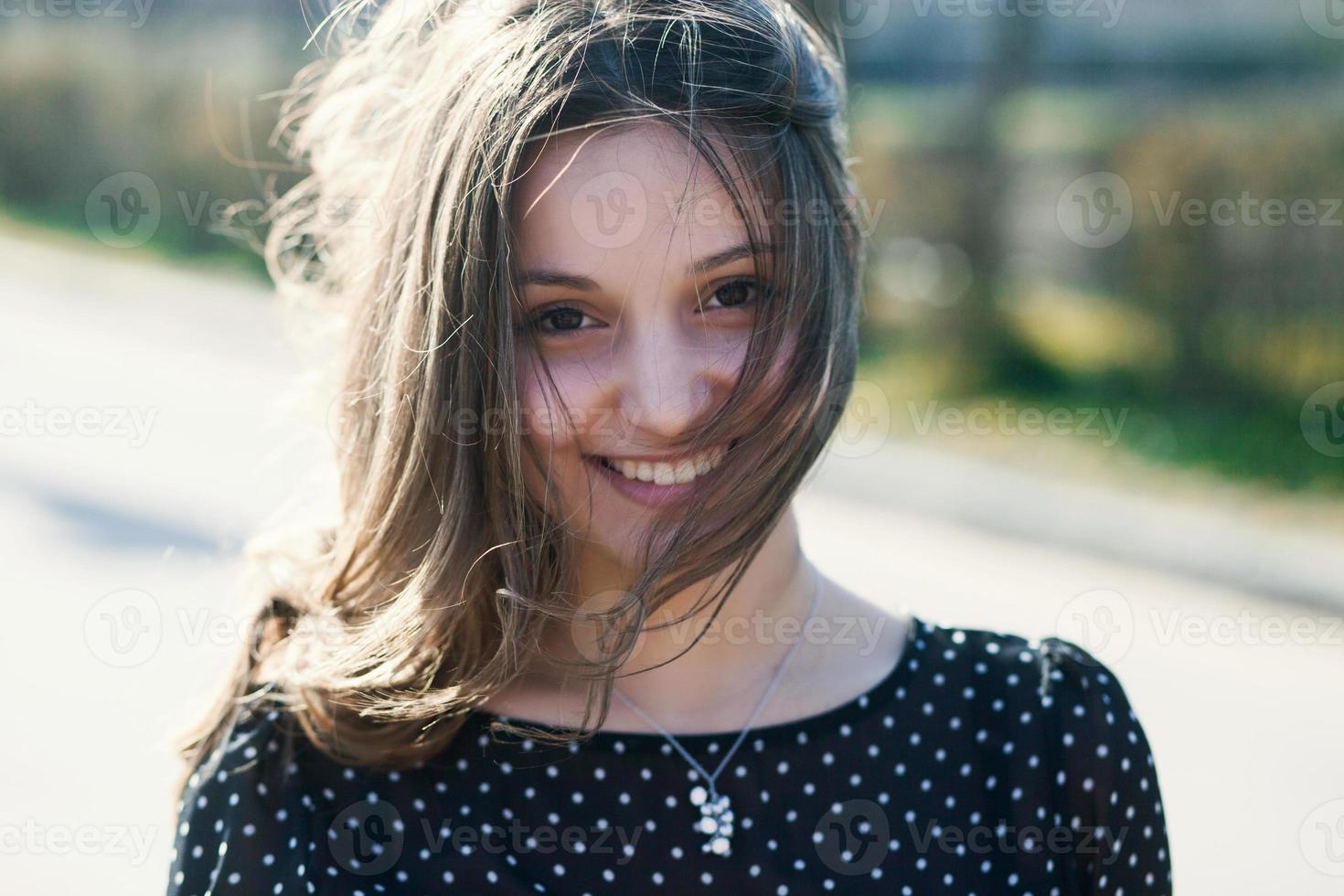 Woman's portrait with a hair moving in the wind. Close-up portrait of young beautiful Russian brunette girl at summer green park. European white woman in dress. photo