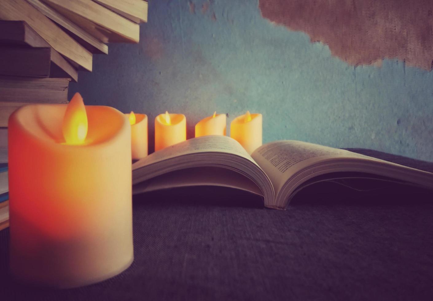 The orange candlelight illuminates the pages of the book, giving the idea of trying to read and study. photo