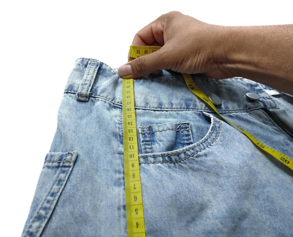 los jeans de mano están tirando de la cinta métrica amarilla. foto