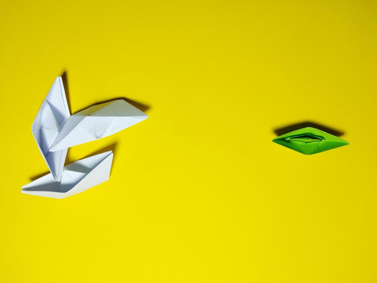 falling green white paper boat The yellow background gives the concept of leadership and ineffective management. causing failure to feel broken, unsuccessful, selfish photo