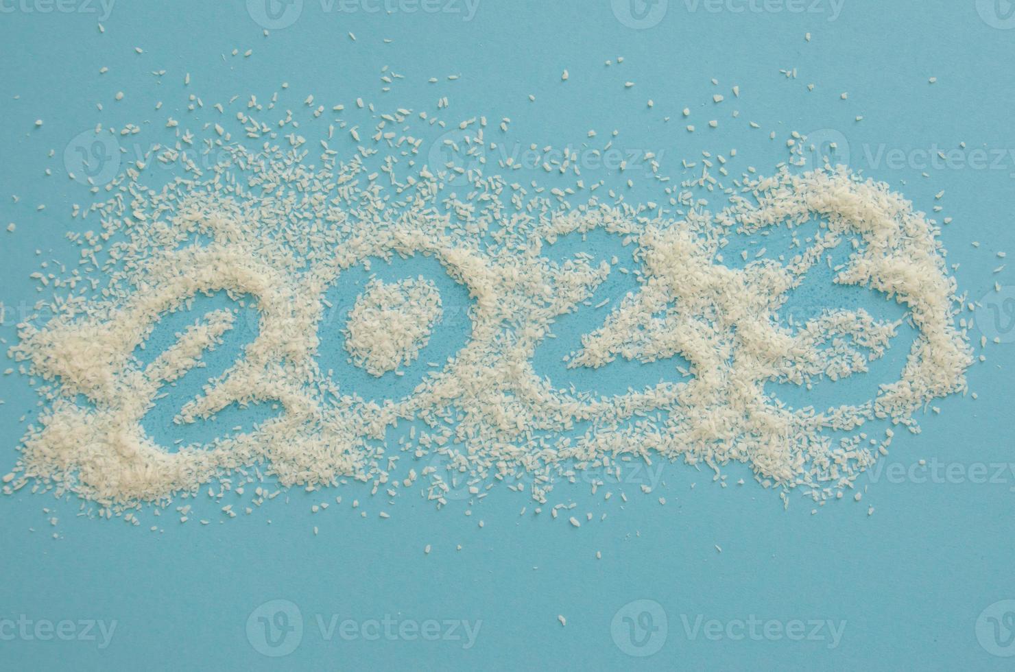 numbers 2023 on a blue background of coconut chips scattered on paper, the concept of the new year photo