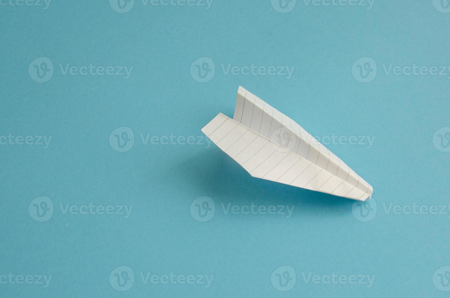 plane made of white paper on a blue background, minimalism photo