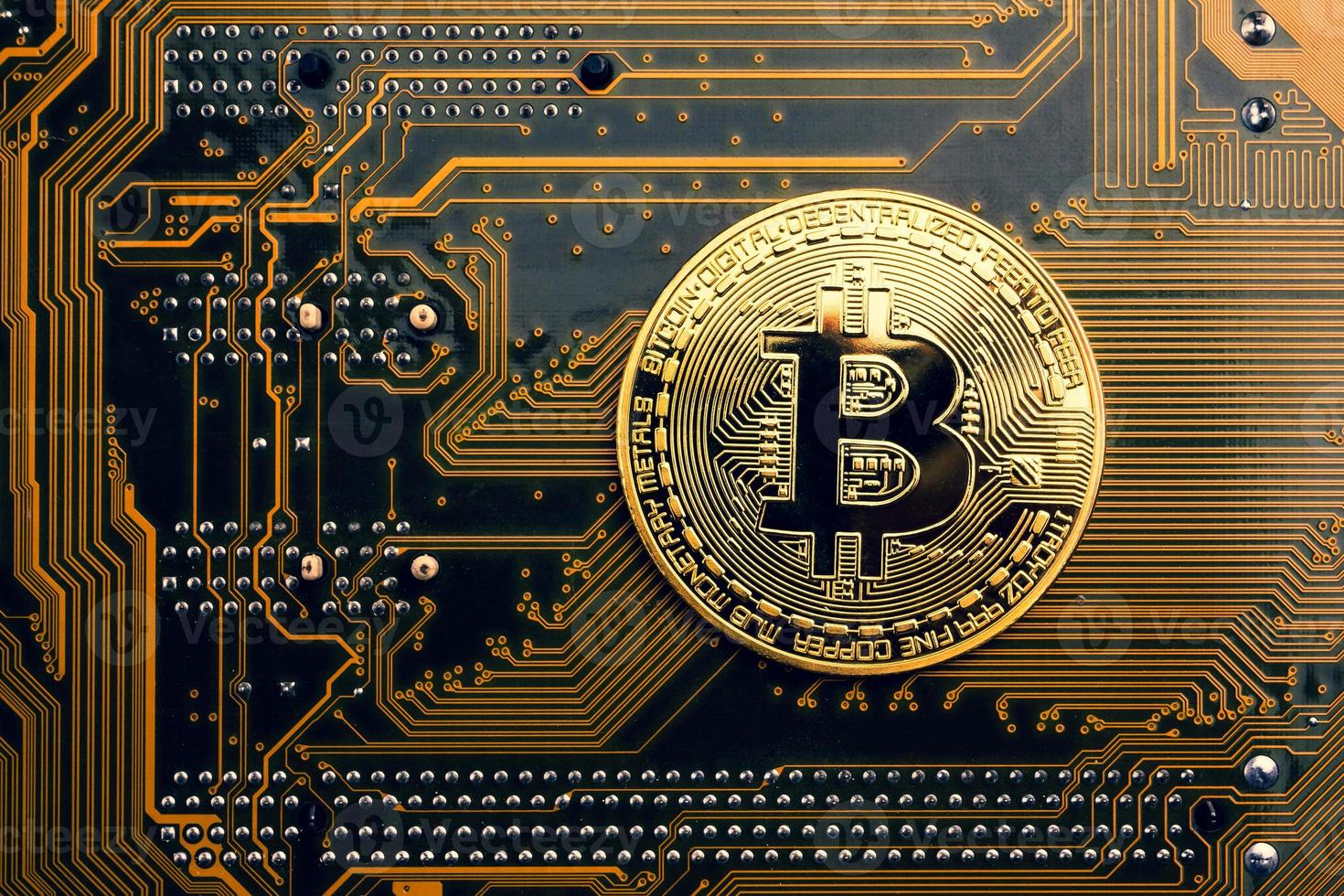 A golden coin with bitcoin symbol on a mainboard. photo