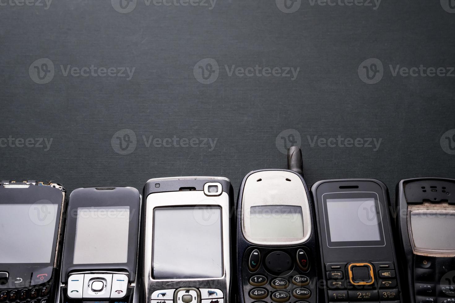 teléfonos celulares viejos y obsoletos en un fondo negro. foto