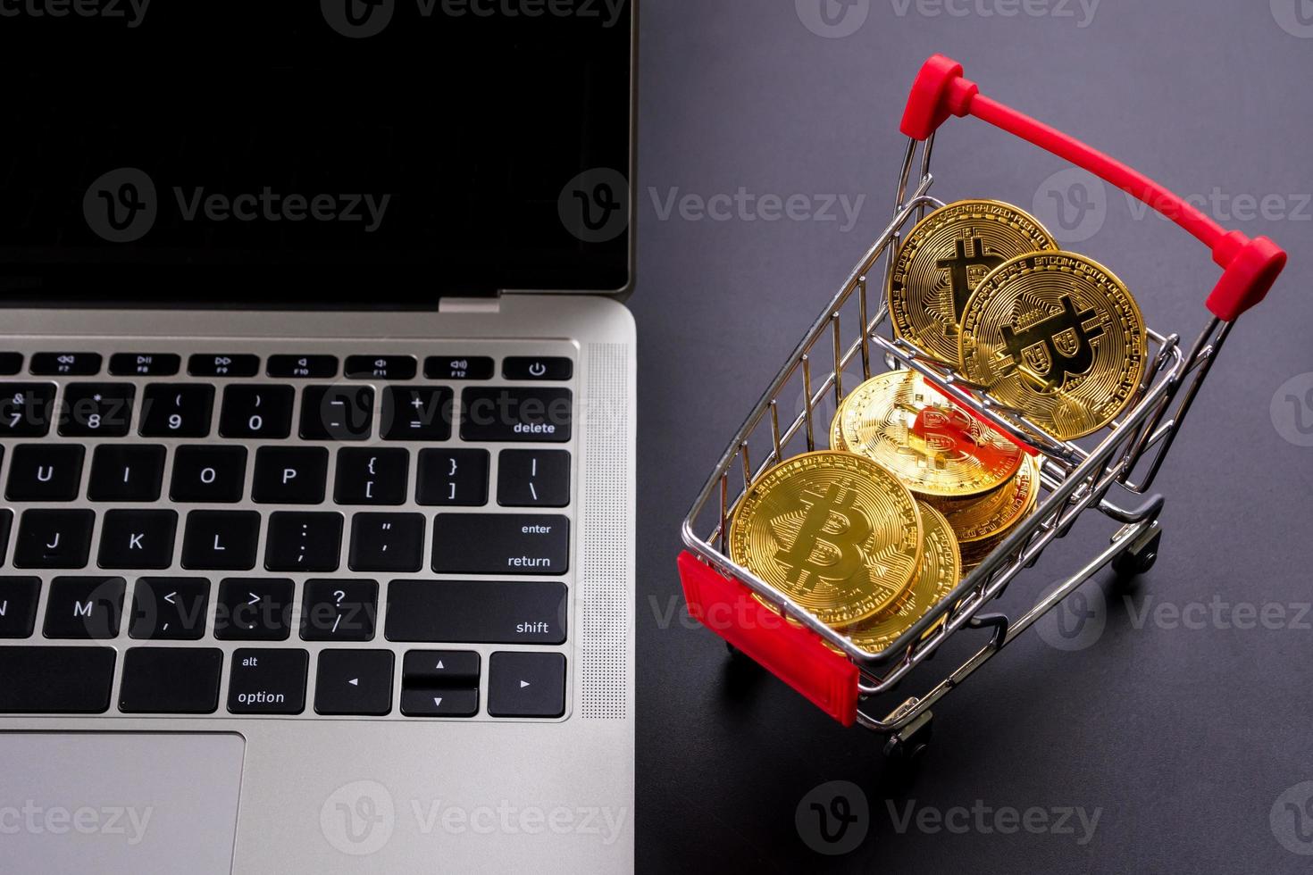 monedas de oro con símbolo de bitcoin en un pequeño carrito de compras y una computadora. foto