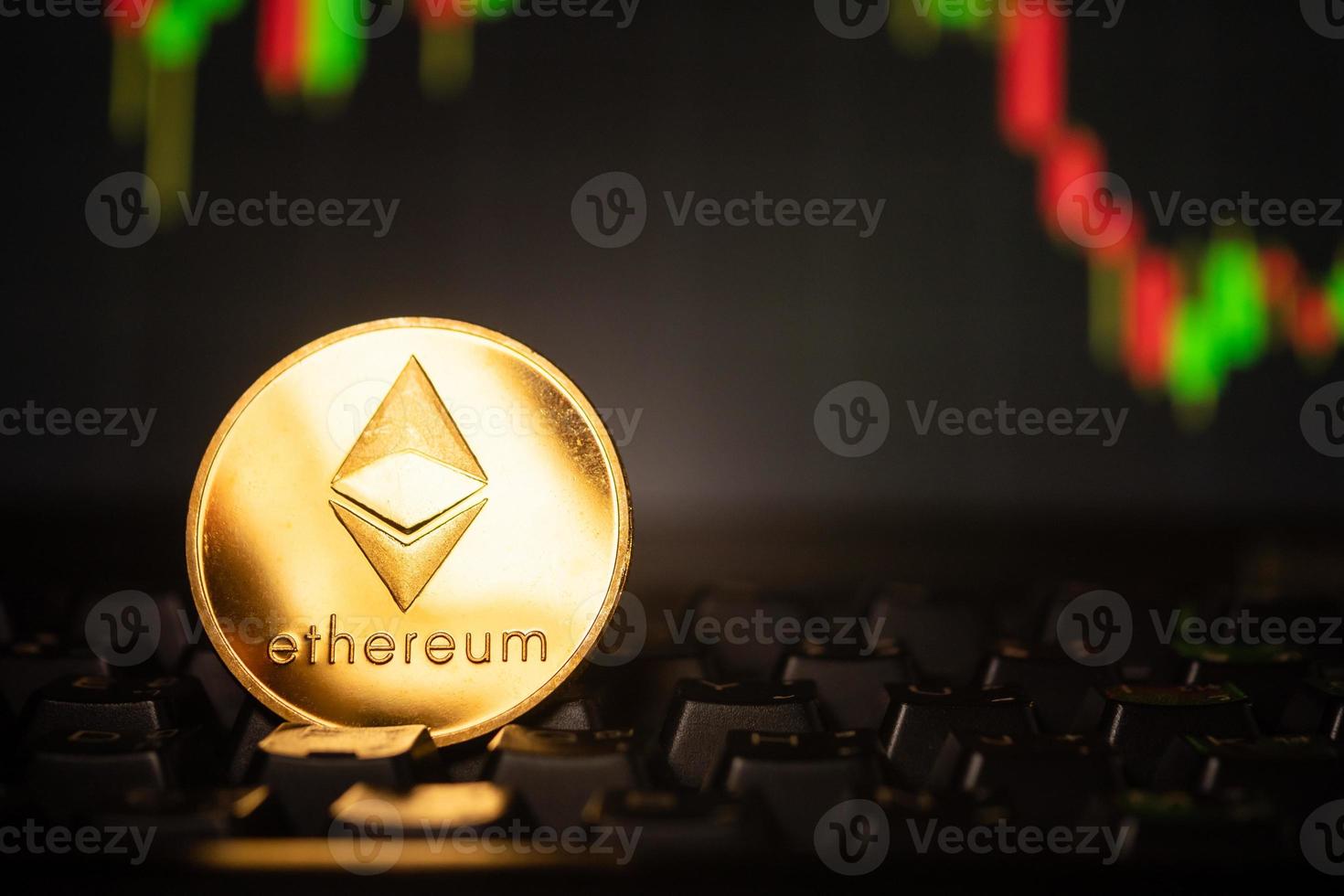 A golden coin with ethereum symbol on computer keyboard with stock graph background. photo