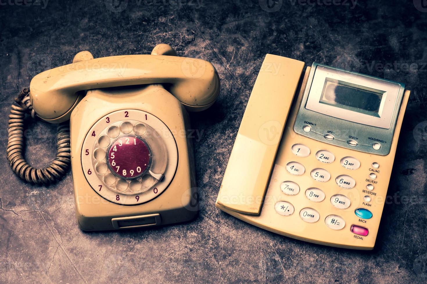 un teléfono antiguo con dial rotatorio y un teléfono fijo sobre un fondo grunge. foto