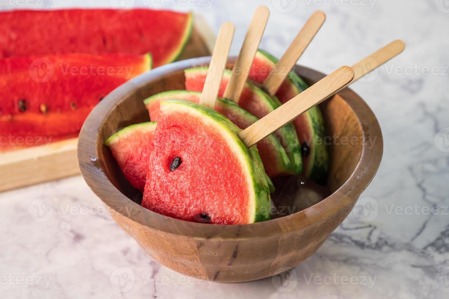 Watermelon slices on sticks with ice cubes. Fresh watermelon popsicles in wooden bowl. photo