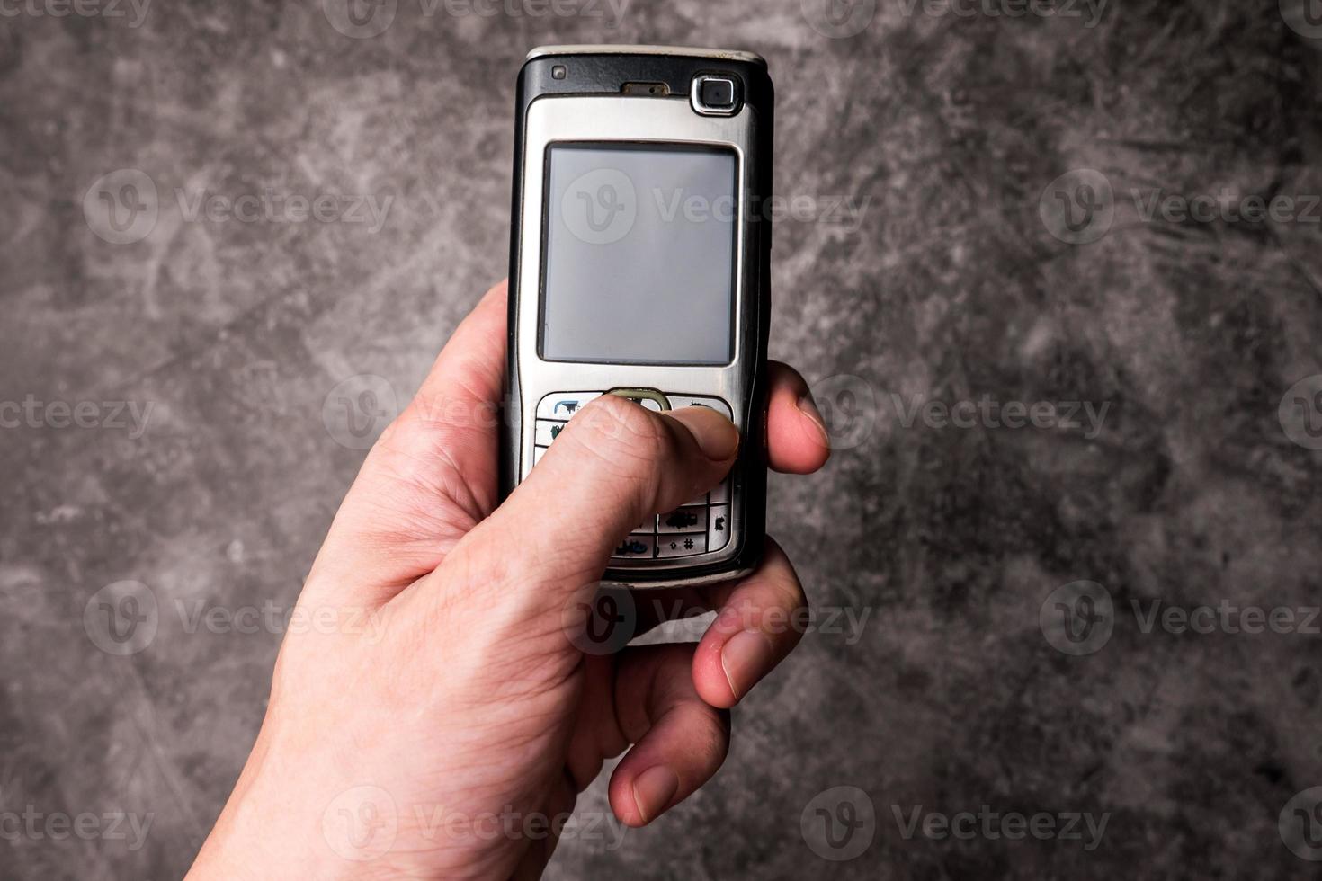 Close up of male hand press on button of an obsolete cellphone. photo