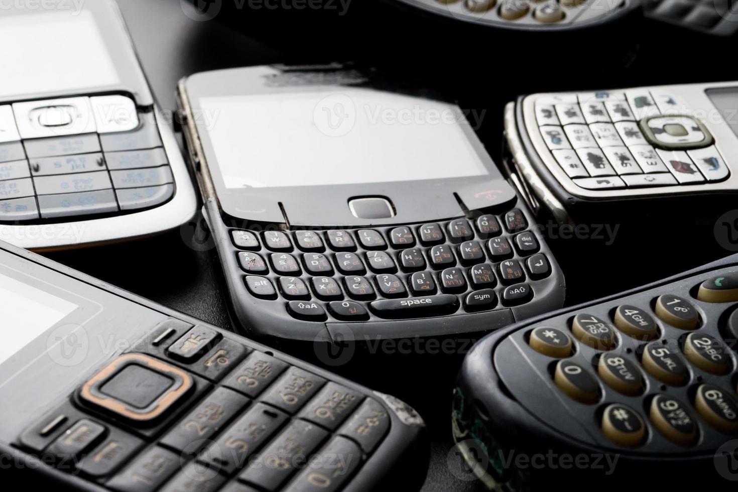 Old and obsoleted cellphones on a black background. photo