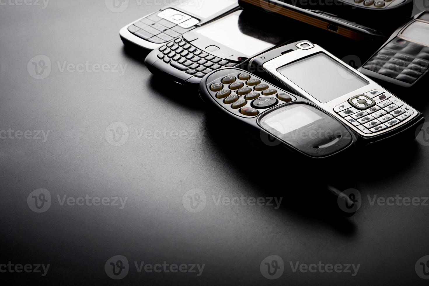 Old and obsoleted cellphones on a black background. photo