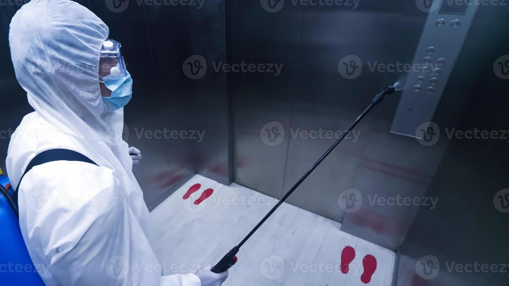 Worker in personal protective equipment suit cleaning in building with spray disinfectant water to remove covid 19 photo